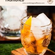 Gorgeous glass filled with maple old fashioned on wooden coaster. The drink is garnished with an orange zest and placed next to a stirring glass.