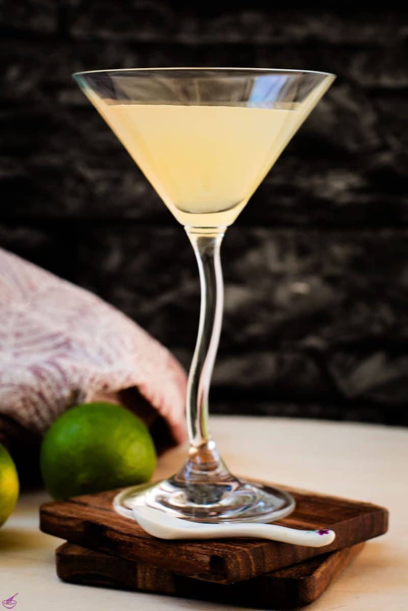 Gorgeous colored daiquiri in cocktail glass. Placed on a wooden board and dark wooden coaster.