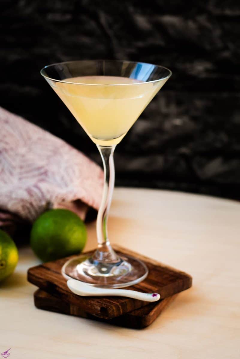 Gorgeous colored daiquiri in cocktail glass. Placed on a wooden board and dark wooden coaster.