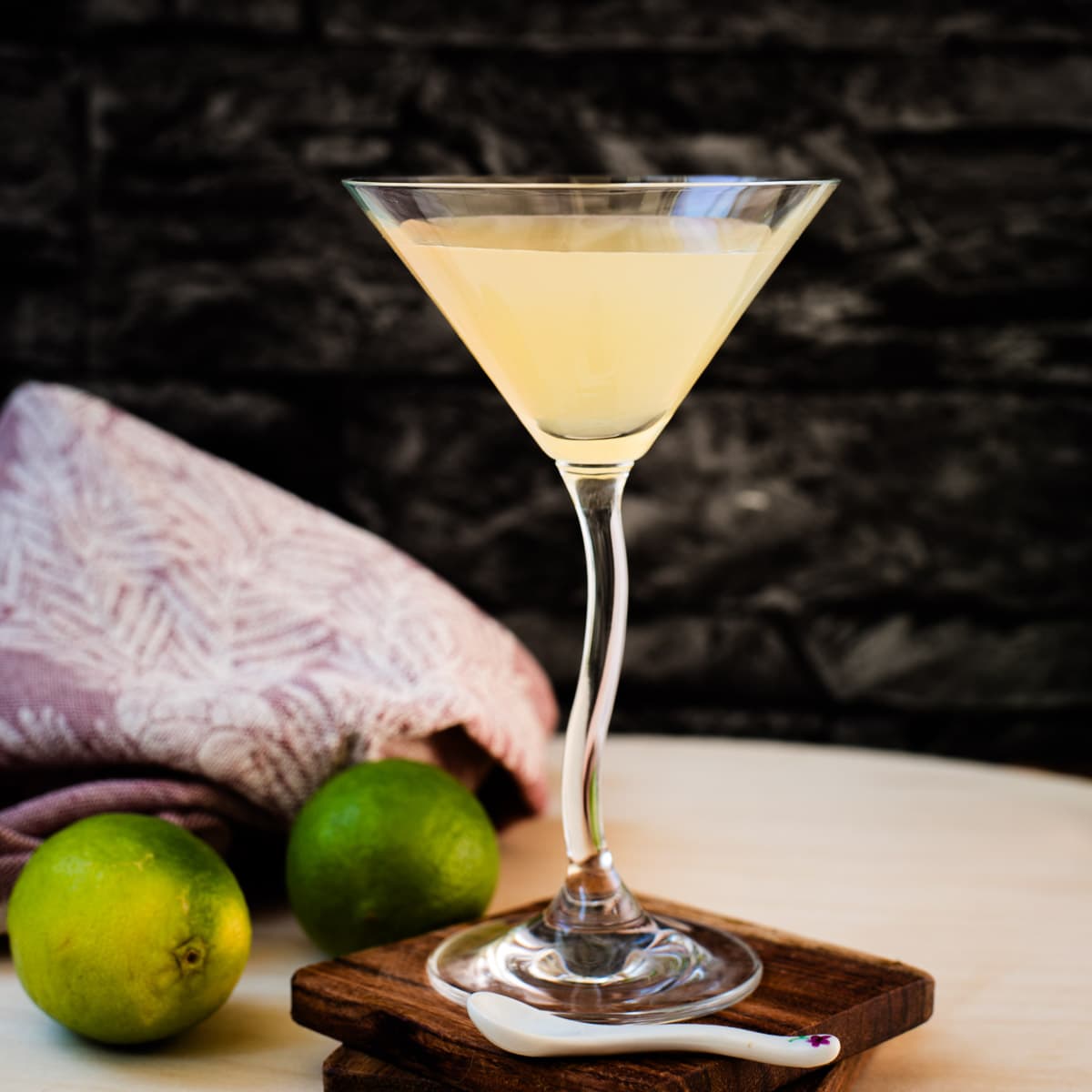 Gorgeous colored daiquiri in cocktail glass. Placed on a wooden board and dark wooden coaster.