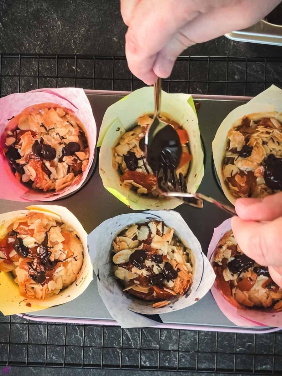 Delicious dried apricot breakfast muffins, with homemade caramel topping, sprinkled with melted chocolate in muffin rack.