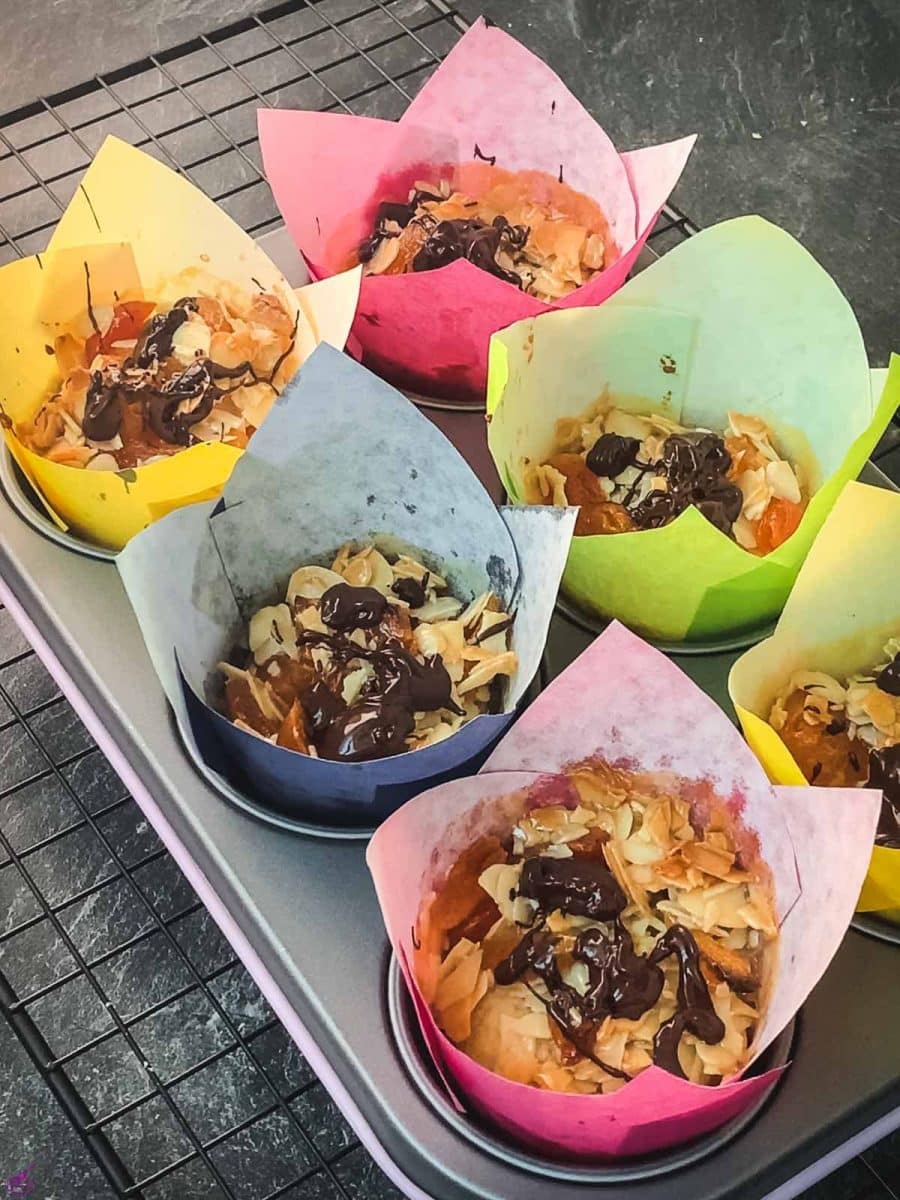 Delicious dried apricot breakfast muffins, with homemade caramel topping, sprinkled with melted chocolate in muffin rack, after baking.