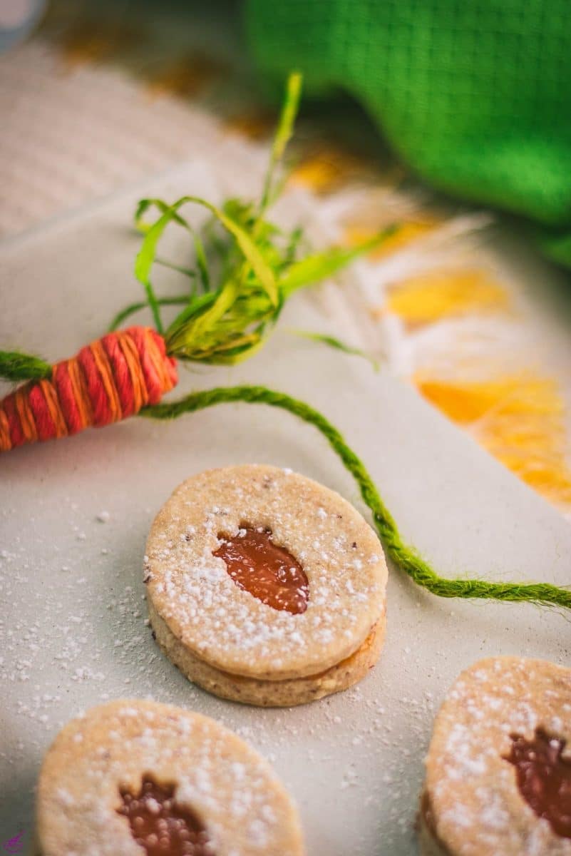 Gorgeous vegan Easter cut out cookies with apricot jam, placed on a white stone plate