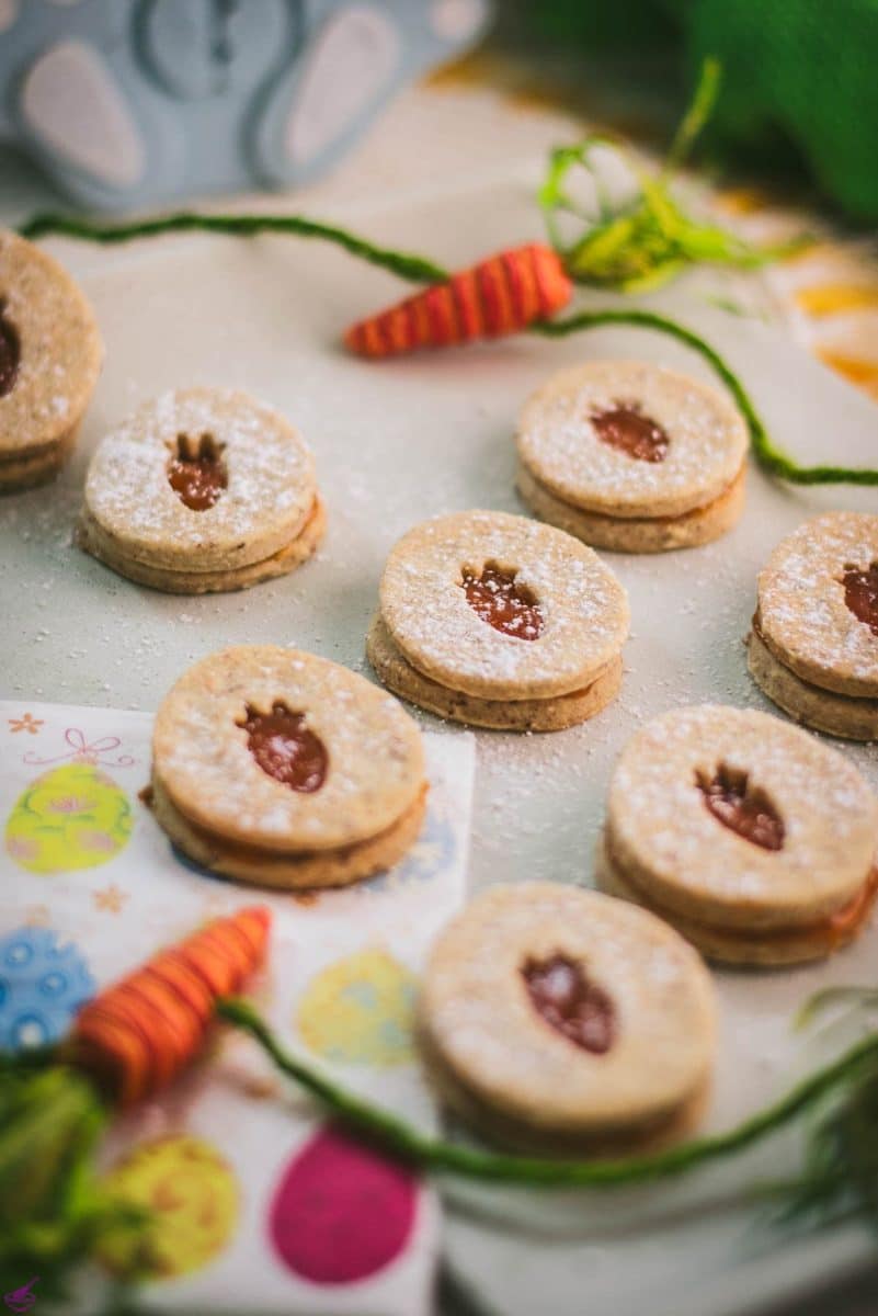 Gorgeous vegan Easter cut out cookies with apricot jam, placed on a white stone plate