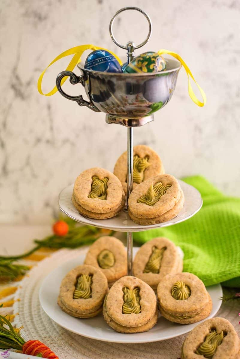 Gorgous cut out Easter cookies with pistachio ganache placed on cute tray.