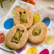 Gorgous cut out Easter cookies with pistachio ganache placed on Easter napkin.