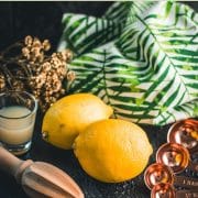 Lemons, placed on dark ground next to lemon juice and lemon squeezer.