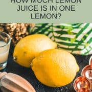 Lemons, placed on dark ground next to lemon juice and lemon squeezer.