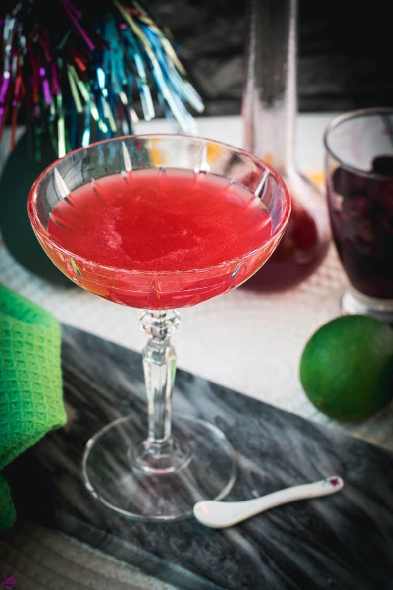 Gorgeous raspberry daiquiri with a vibrant red color placed on marble plate.