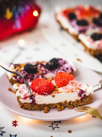 Delicious no-bake 4th of July fruit tart slices, placed on pink plate and two forks that wanna grab a bite.