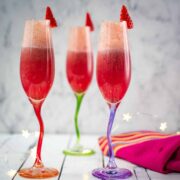 Gorgeous colored champagne flutes filled with vibrant berry mimosa.