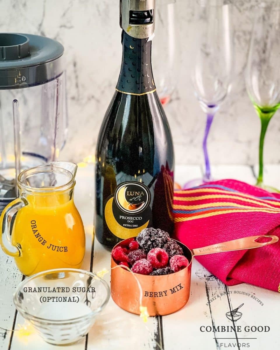 Ingredients for berry mimosa - orange juice, sparkling wine, berry mix and granulated sugar.