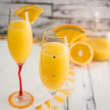 Gorgeous mimosa, garnished with orange slice in cute glass with small gems.