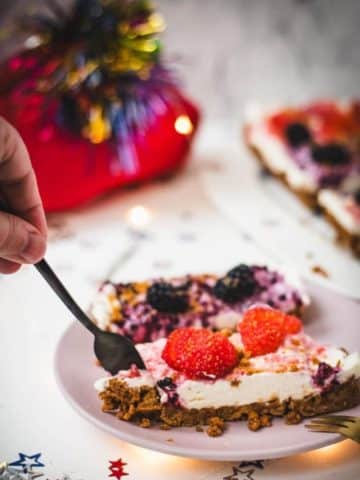 Delicious no-bake 4th of July fruit tart slices, placed on pink plate and two forks that wanna grab a bite.