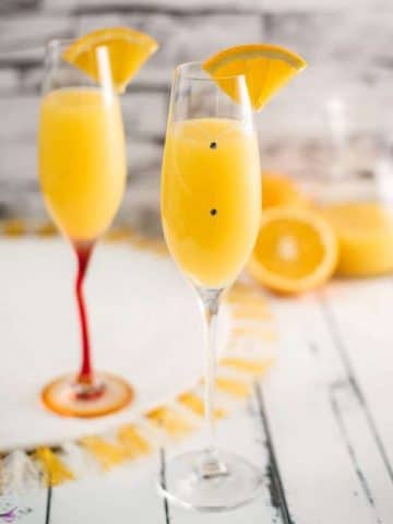 Gorgeous mimosa, garnished with orange slice in cute glass with small gems.