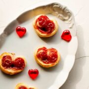 Beautiful puff pastry hearts with strawberry jam, trapped on an elegant, old serving platter. Decorated with glass hearts.