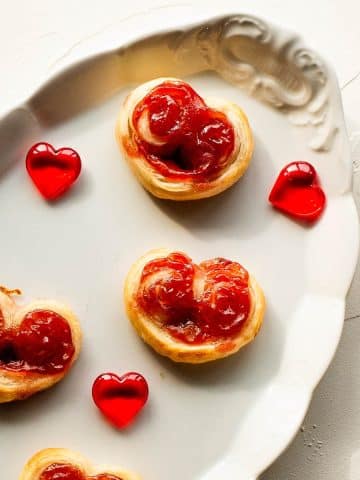 Beautiful puff pastry hearts with strawberry jam, trapped on an elegant, old serving platter. Decorated with glass hearts.