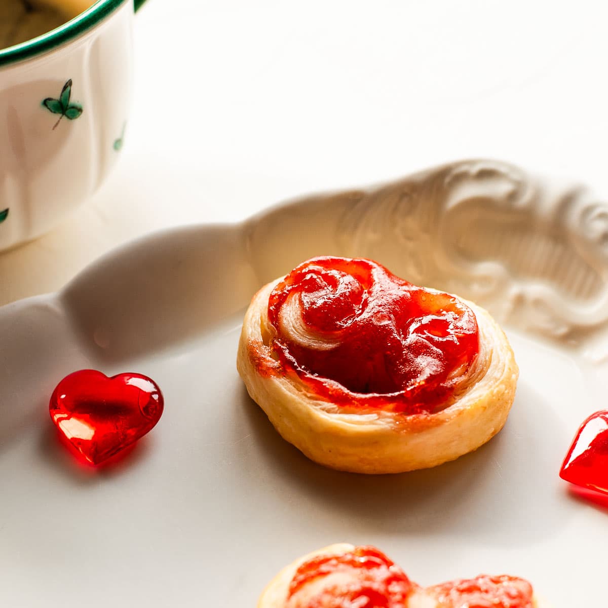 Beautiful puff pastry hearts with strawberry jam, trapped on an elegant, old serving platter. Decorated with glass hearts.