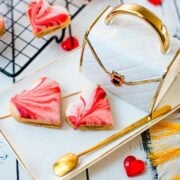 Gorgeous heart shaped sugar cookies with marbled icing, and filled with fig jam. Placed on gorgeous white golden serving plate.