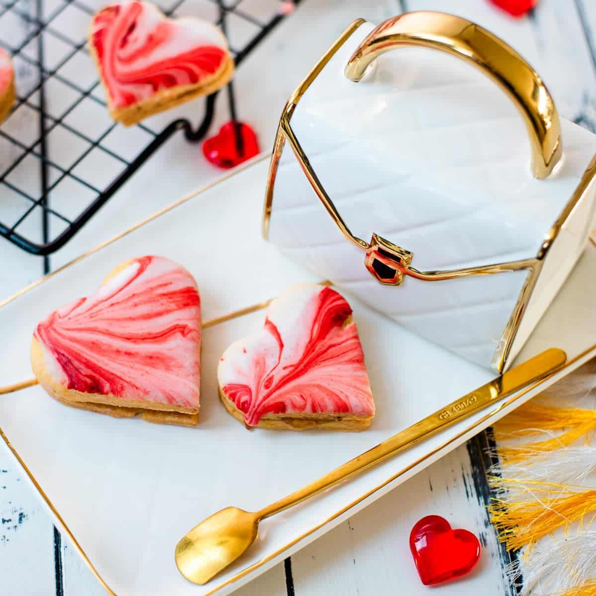 Gorgeous heart shaped sugar cookies with marbled icing, and filled with fig jam. Placed on gorgeous white golden serving plate.