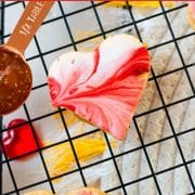 Gorgeous heart shaped sugar cookies with marbled icing, and filled with fig jam. Placed on cooling rack next to half a tablespoon of fig jam.