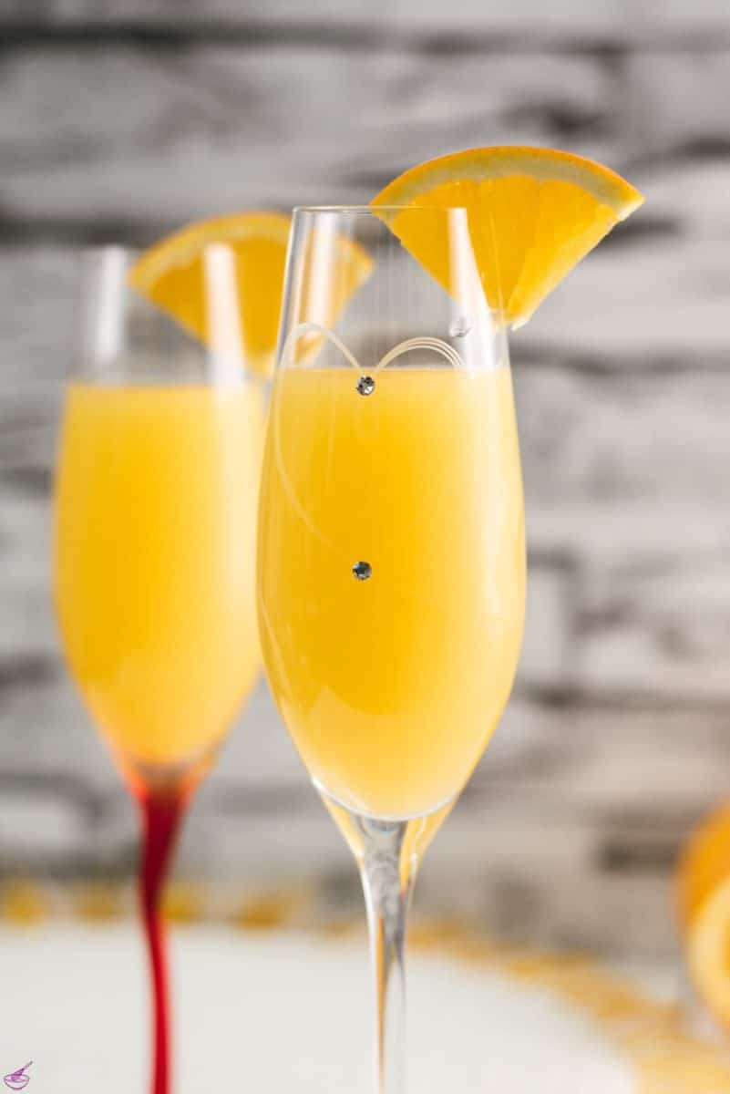 Gorgeous mimosa, garnished with orange slice in cute glass with small gems.