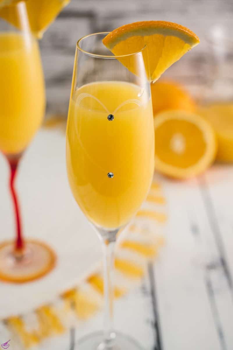 Gorgeous mimosa, garnished with orange slice in cute glass with small gems.