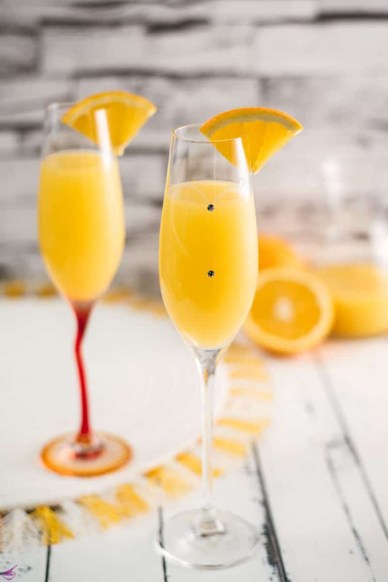 Gorgeous mimosa, garnished with orange slice in cute glass with small gems.