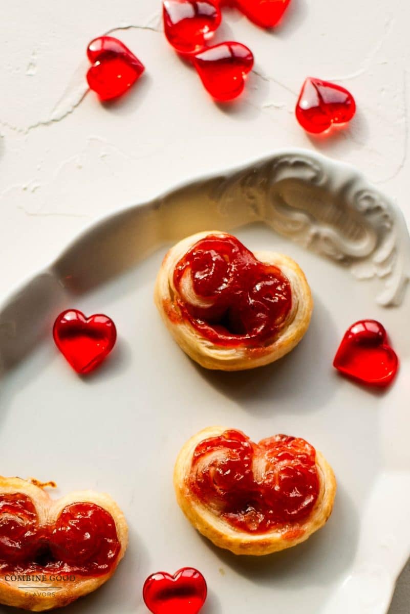 Beautiful puff pastry hearts with strawberry jam, trapped on an elegant, old serving platter. Decorated with glass hearts.