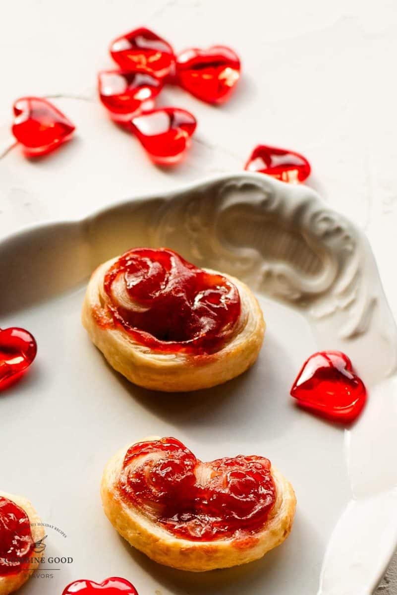 Beautiful puff pastry hearts with strawberry jam, trapped on an elegant, old serving platter. Decorated with glass hearts.