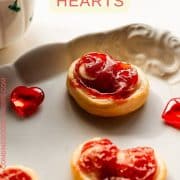 Beautiful puff pastry hearts with strawberry jam, trapped on an elegant, old serving platter. Decorated with glass hearts.