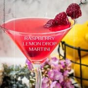 Cocktail glass filled with delicious raspberry lemon drop martini and garnished with raspberries on a cocktail spike.