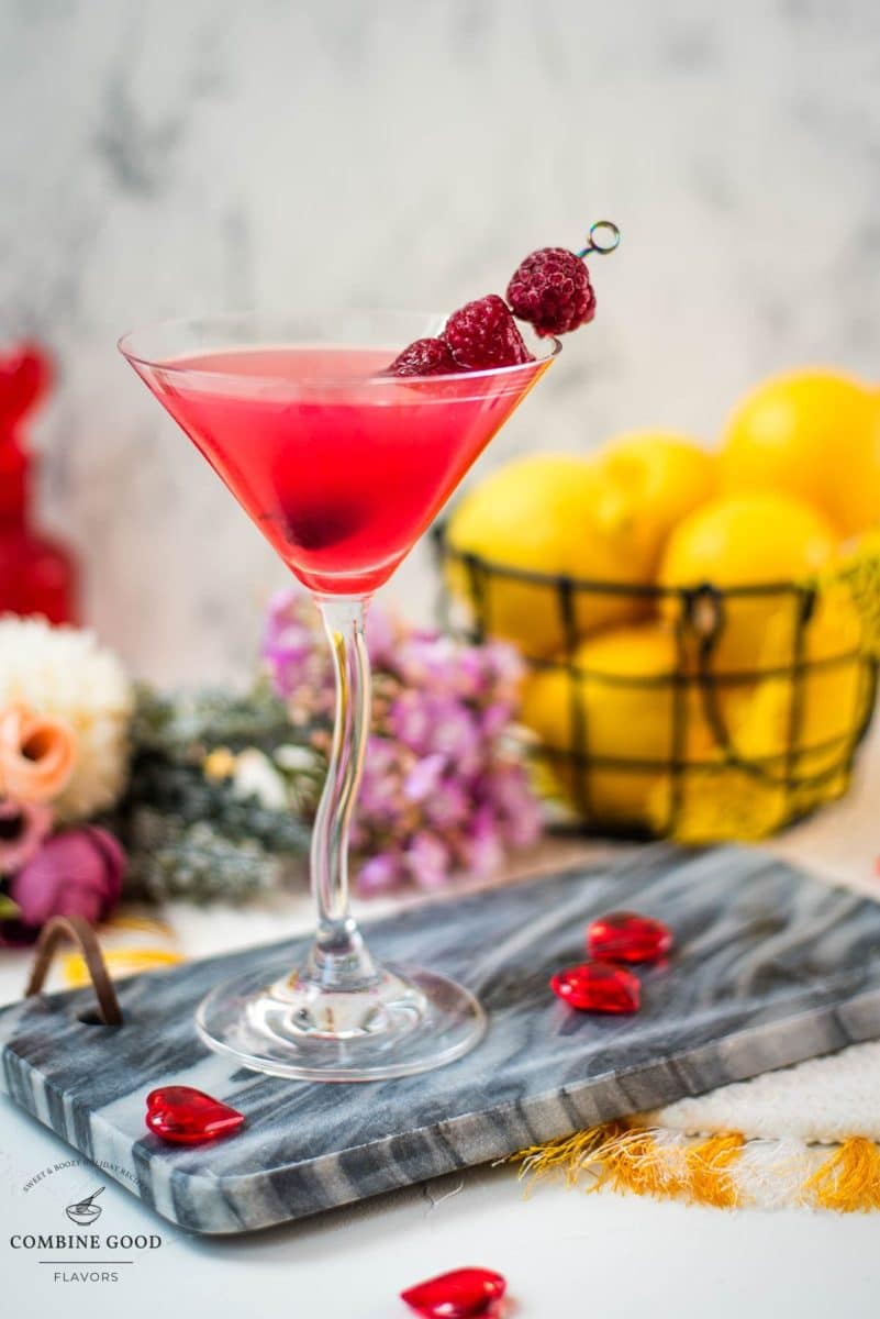 Cocktail glass filled with delicious raspberry lemon drop martini and garnished with raspberries on a cocktail spike.