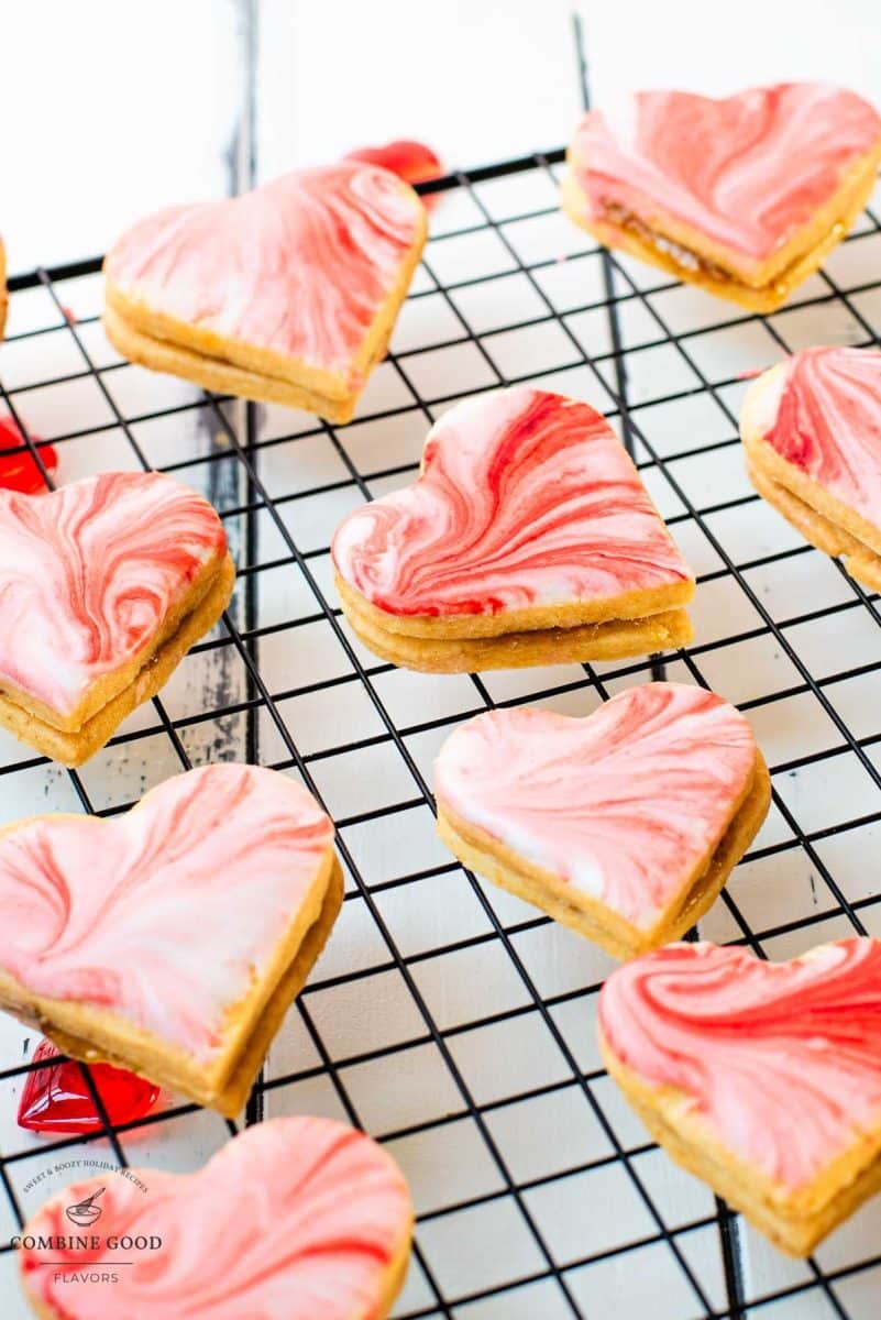 Gorgeous heart shaped sugar cookies with marbled icing, and filled with fig jam. Placed on cooling rack.