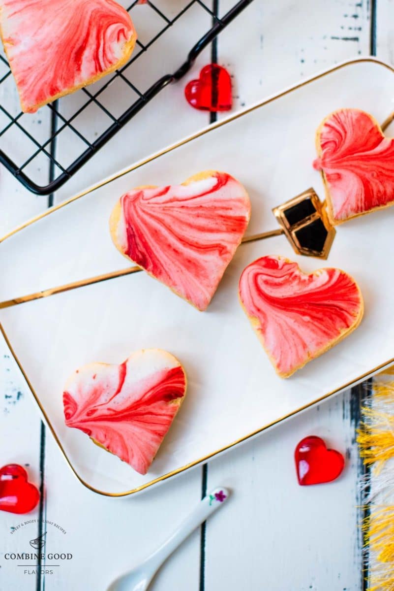 Gorgeous heart shaped sugar cookies with marbled icing, and filled with fig jam. Placed on gorgeous white golden serving plate.