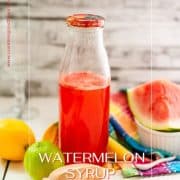 Preserving bottle filled with vibrant watermelon syrup placed on white wooden ground.
