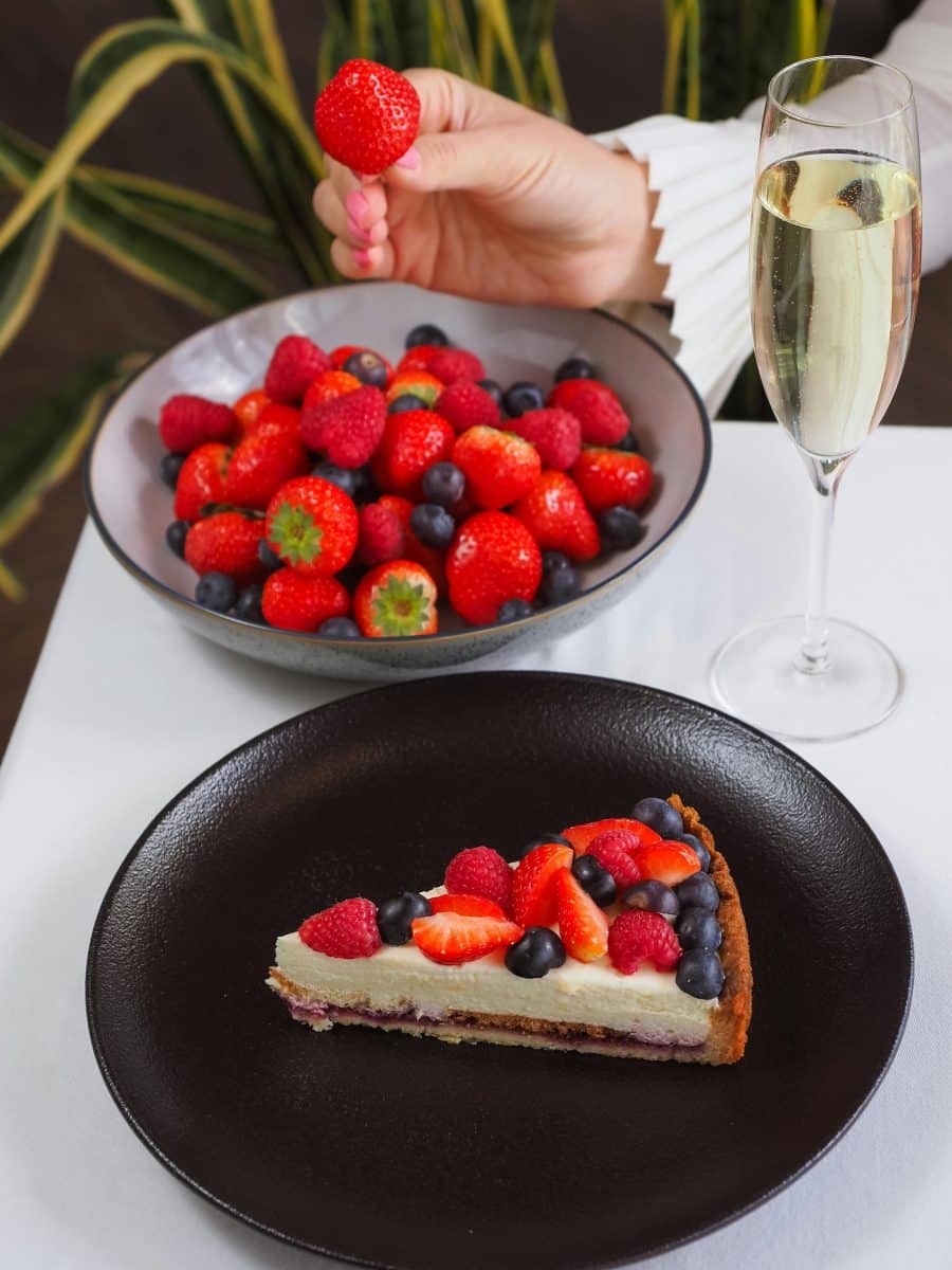 Strawberry bowl, next to berry tart and a glass of wine.