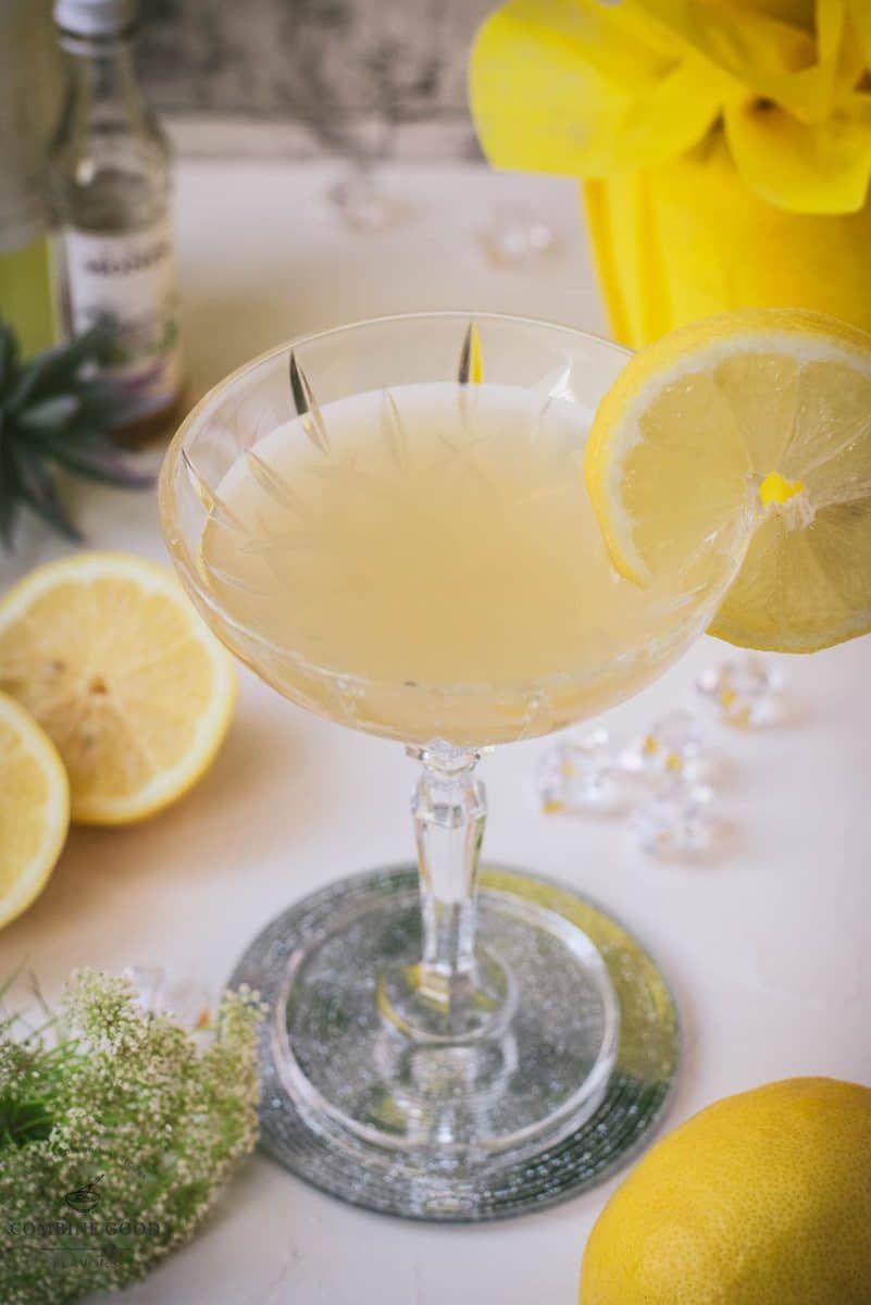 Gorgeous Limoncello Martini cocktail with elderflower syrup. Garnished with a lemon slice and placed on a mirrored coaster.