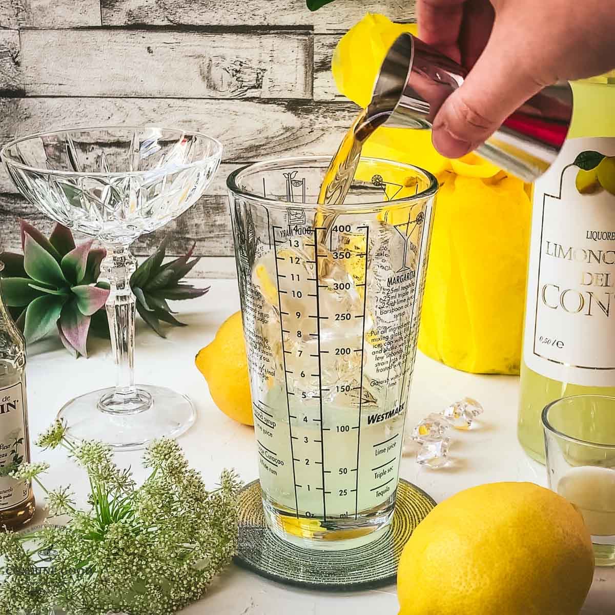 Adding elderflower syrup to the cocktail shaker.