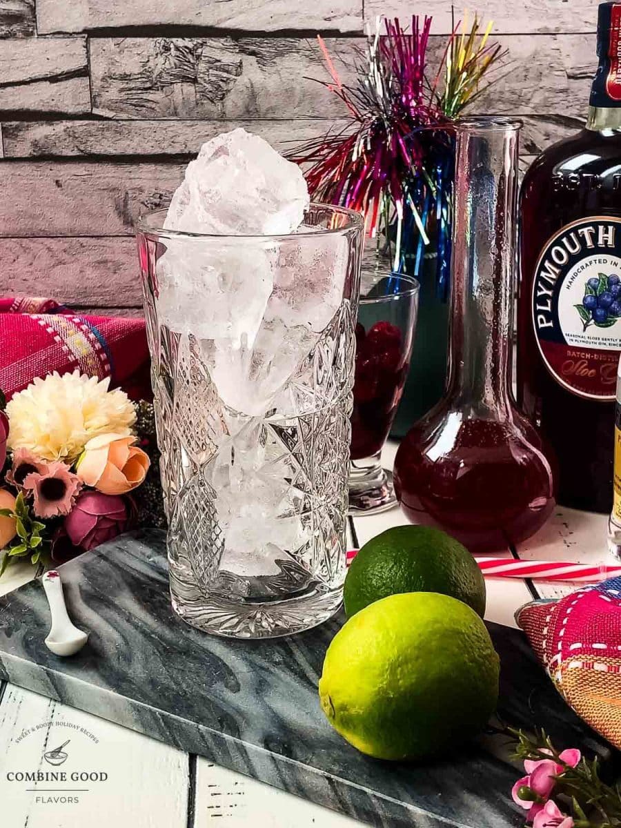 Highball glass filled with cubed ice, placed on marbled plate.