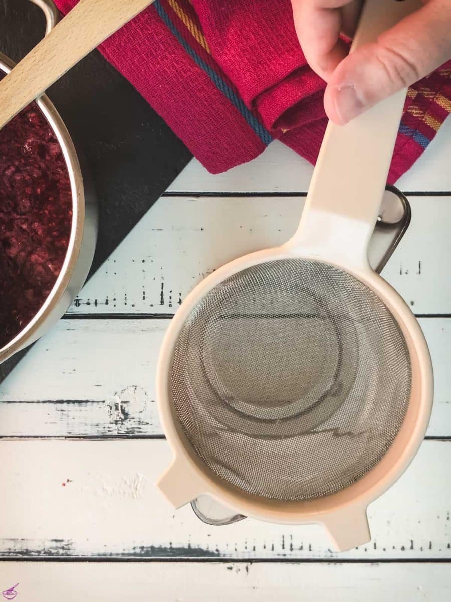 Placing a fine-meshed sieve on top of a tall container.