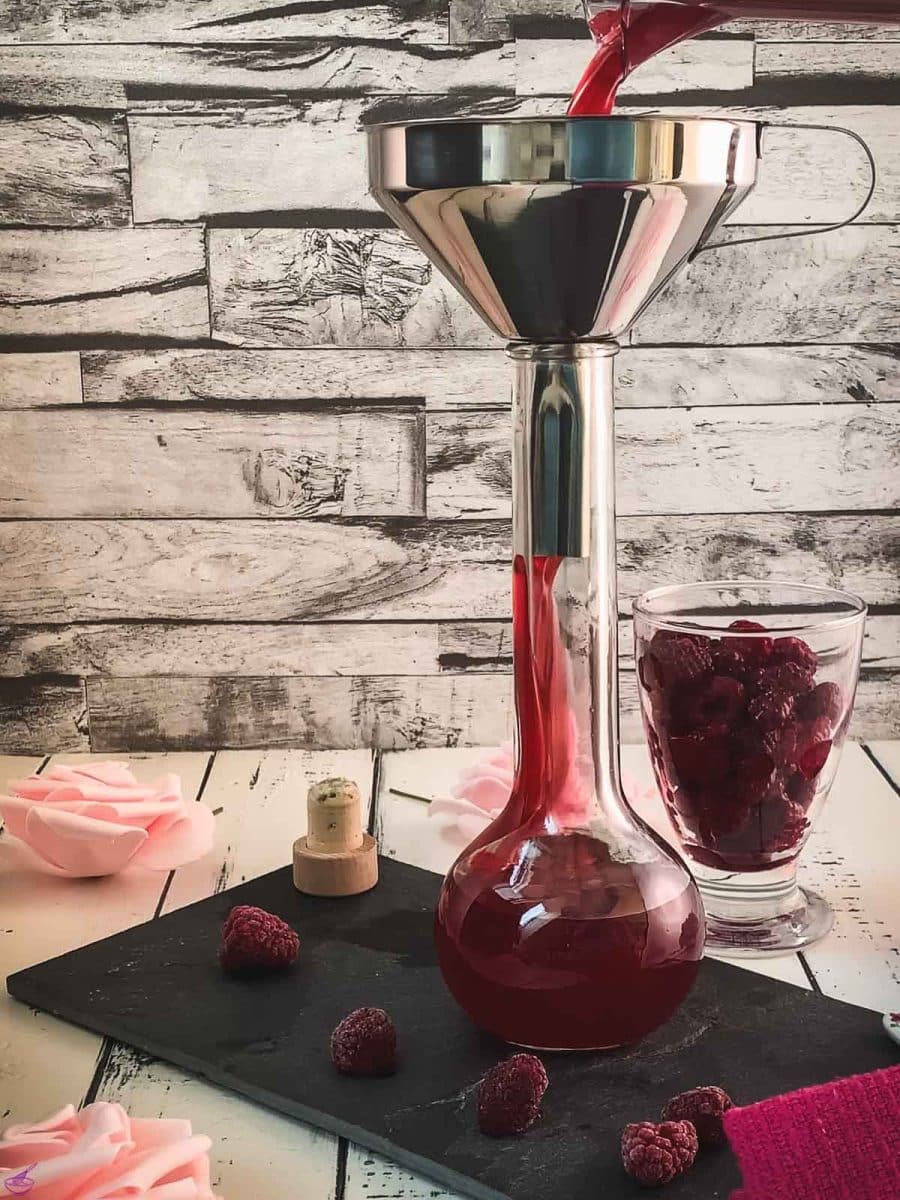 Funnel on top of the glass flask while pouring the raspberry syrup into it.