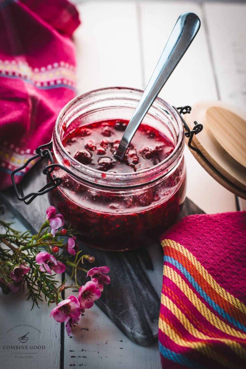 Preserving jar, filled with delicious uncooked raspberry syrup placed on a marbled plate.