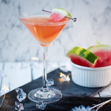 Gorgeous watermelon martini with a watermelon garnish, placed on a black slate plate.