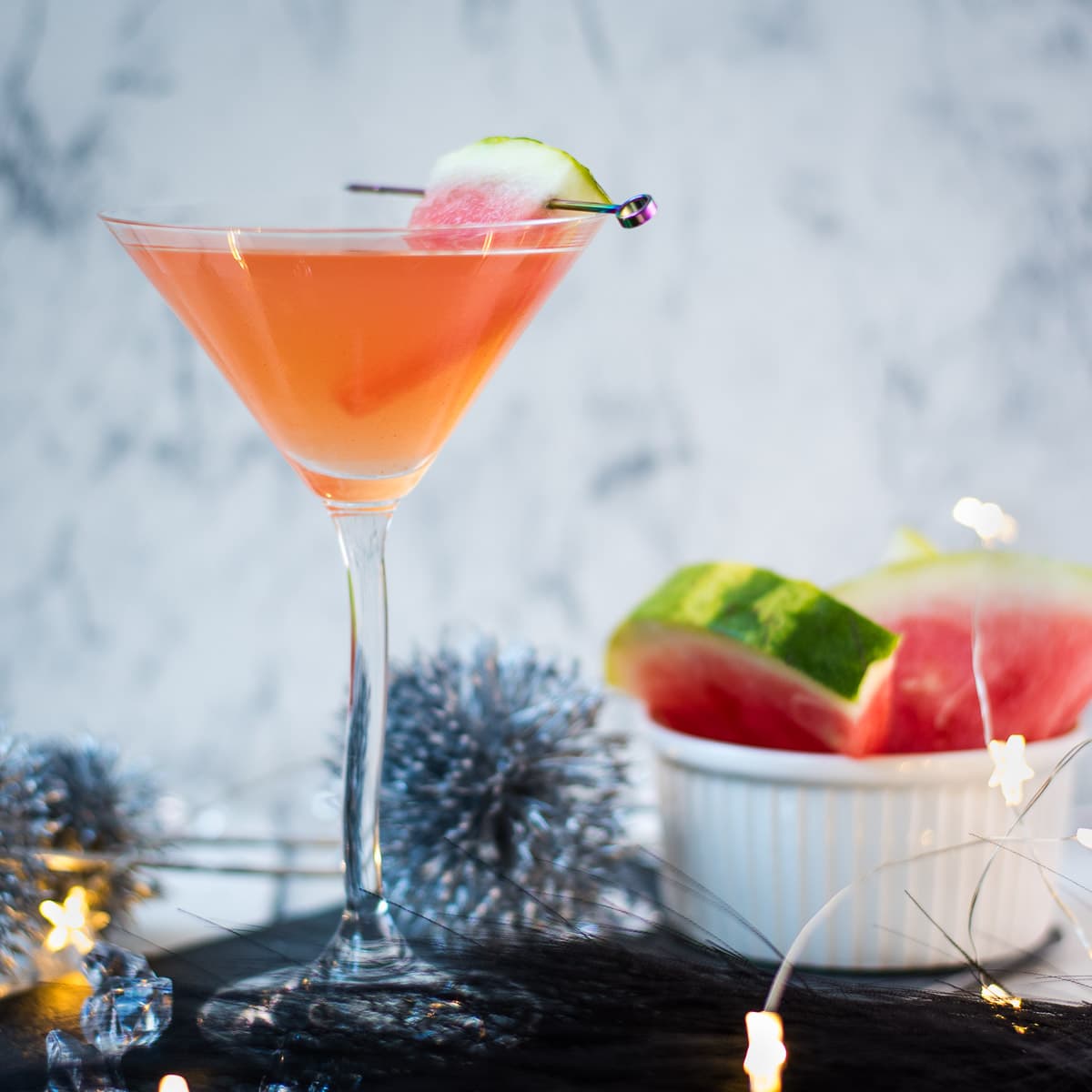 Gorgeous watermelon martini with a watermelon garnish, placed on a black slate plate.