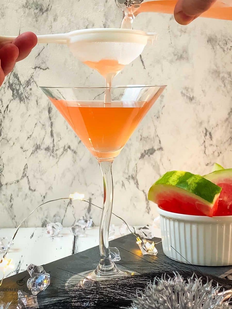 Fine-straining the watermelon martini into your serving glass.