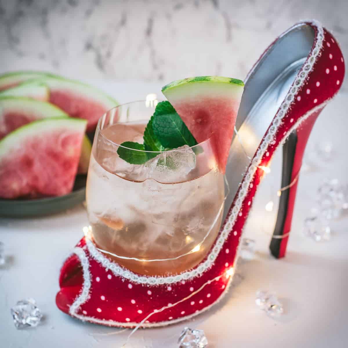 Delicious watermelon spritz with Prosecco placed in a red and white spotted high heel.