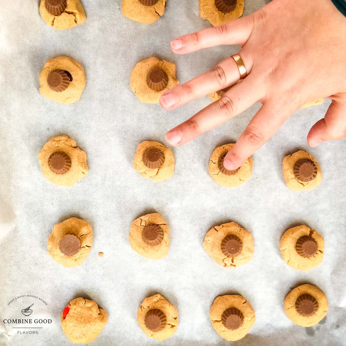 Placing one peanut butter cup on top of each baked peanut butter cookie.