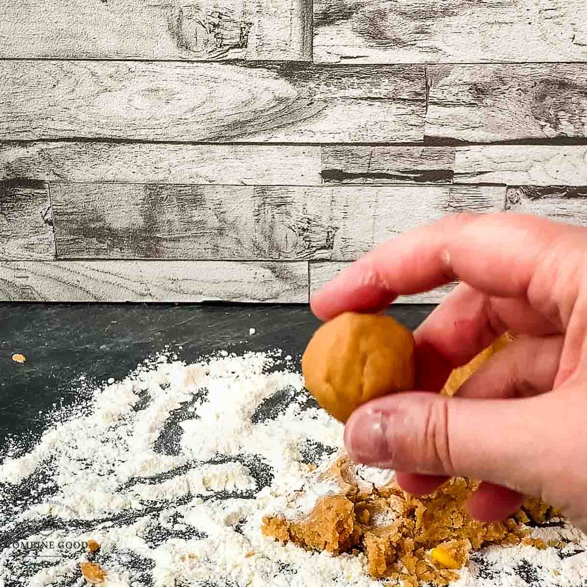 Dough ball between thumb and forefinger show the size of the peanut butter cookie.