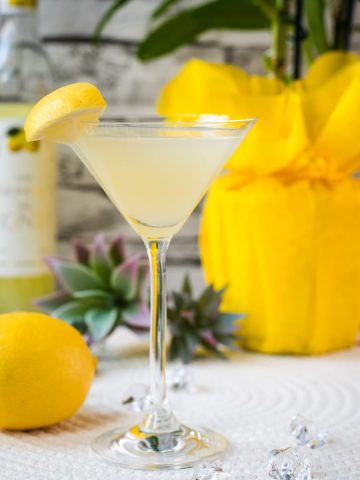 Gorgeous cocktail glass filled with a vibrant limoncello martini, garnished with a lemon wedge.